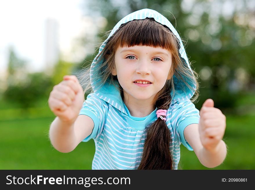 Full length outdoor portrait of adorable child girl in blue jacket with hood posing with clenched fists. Full length outdoor portrait of adorable child girl in blue jacket with hood posing with clenched fists