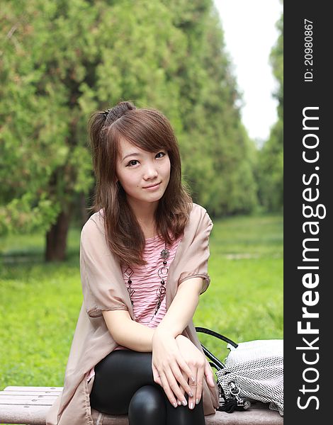 A lovely asian woman in a parkâ€™ grass plot.