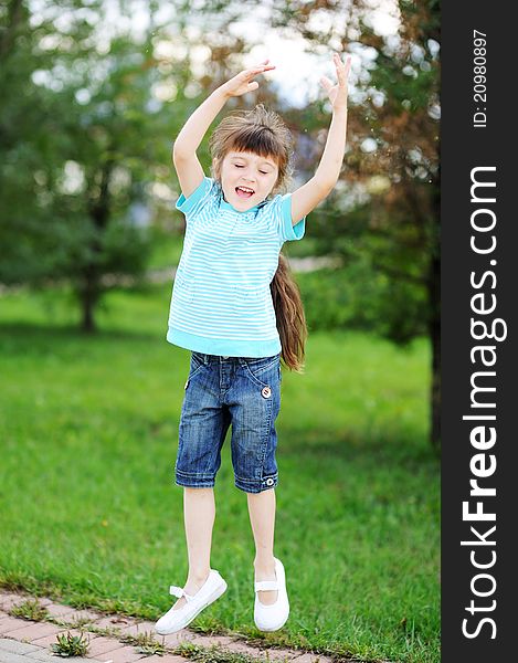 Adorable happy child girl is jumping in the air outdoors