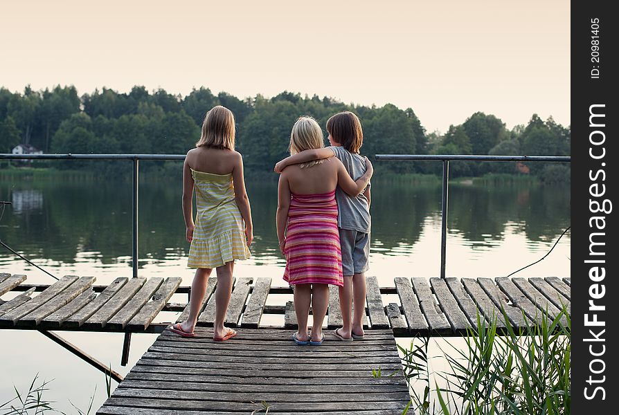 Three children standing on platform, looking at the distance. Three children standing on platform, looking at the distance