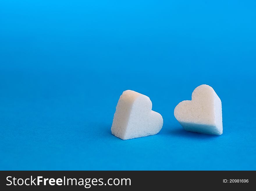 Lump of sugar shaped heart with blue background.