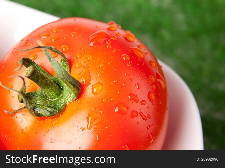 Closeup imge of red tomato on white plate with water drops. Closeup imge of red tomato on white plate with water drops