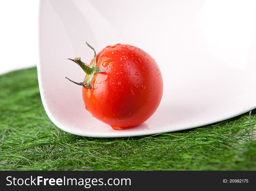 Red tomato on white plate with water drops. Red tomato on white plate with water drops