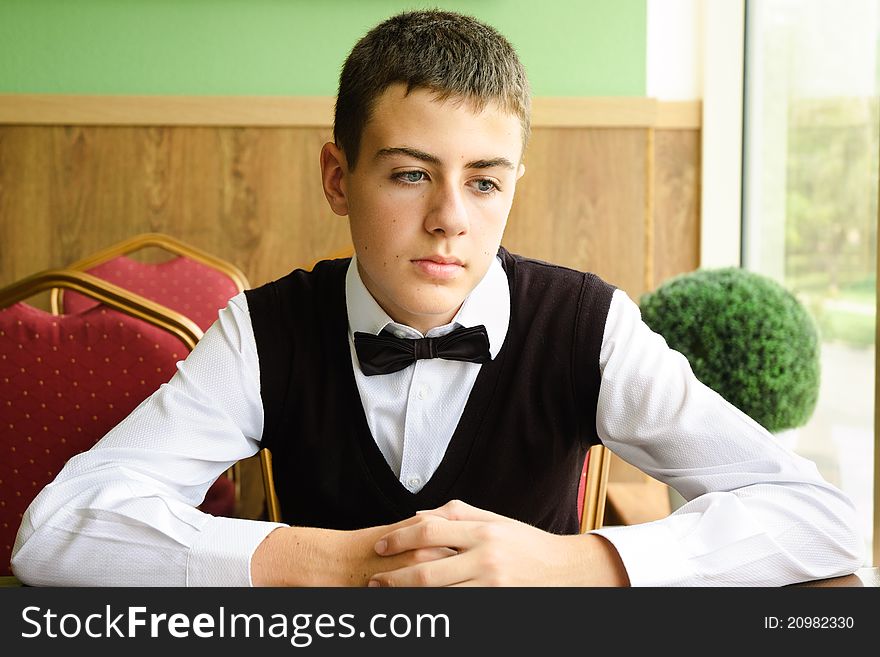 Upset teenager boy waiting for friends in a cafe in morning. Upset teenager boy waiting for friends in a cafe in morning