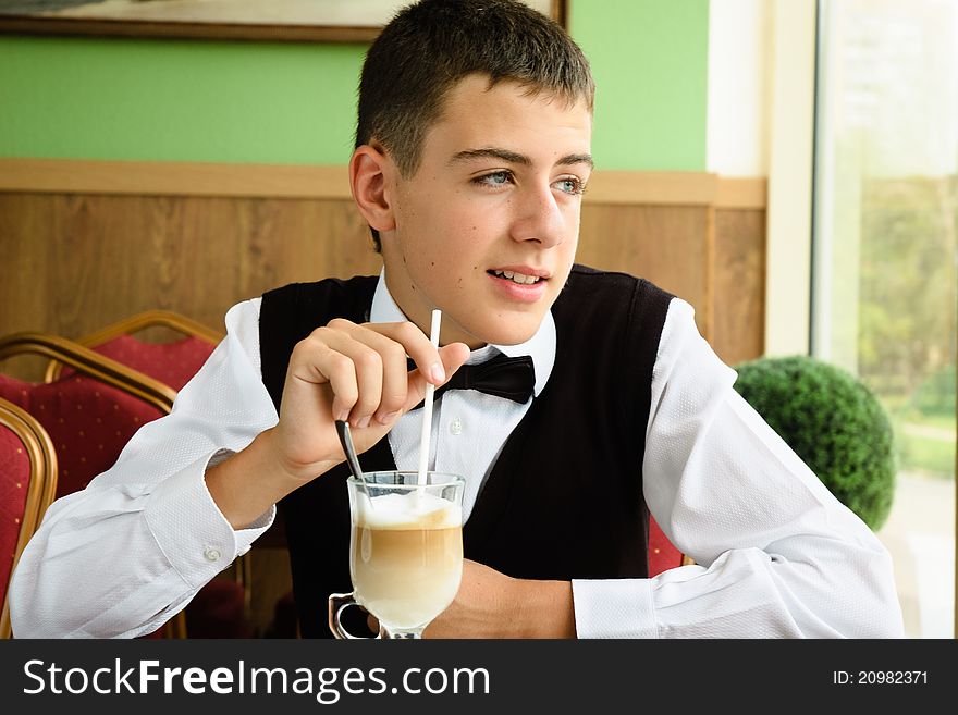 A teenager boy enjoying coffee in a cafe watching in window