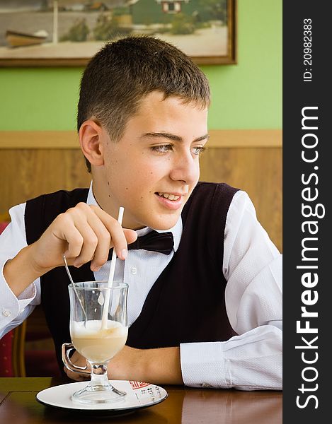 A teenager boy enjoying coffee in a cafe watching in window