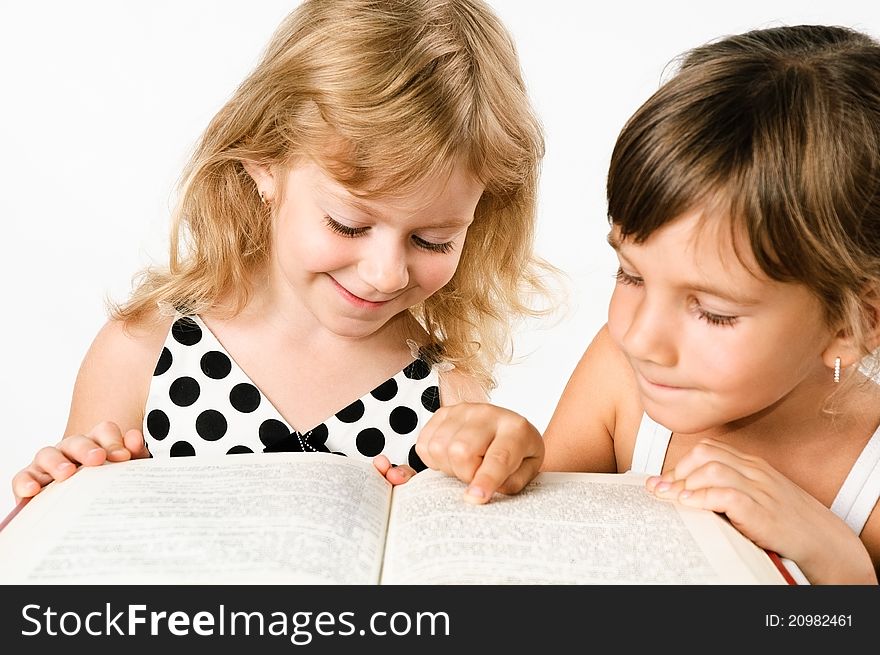 Two preschooler girls reding a book isolated on white. Two preschooler girls reding a book isolated on white