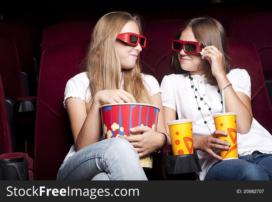 Two beautiful girls watching a movie at the cinema