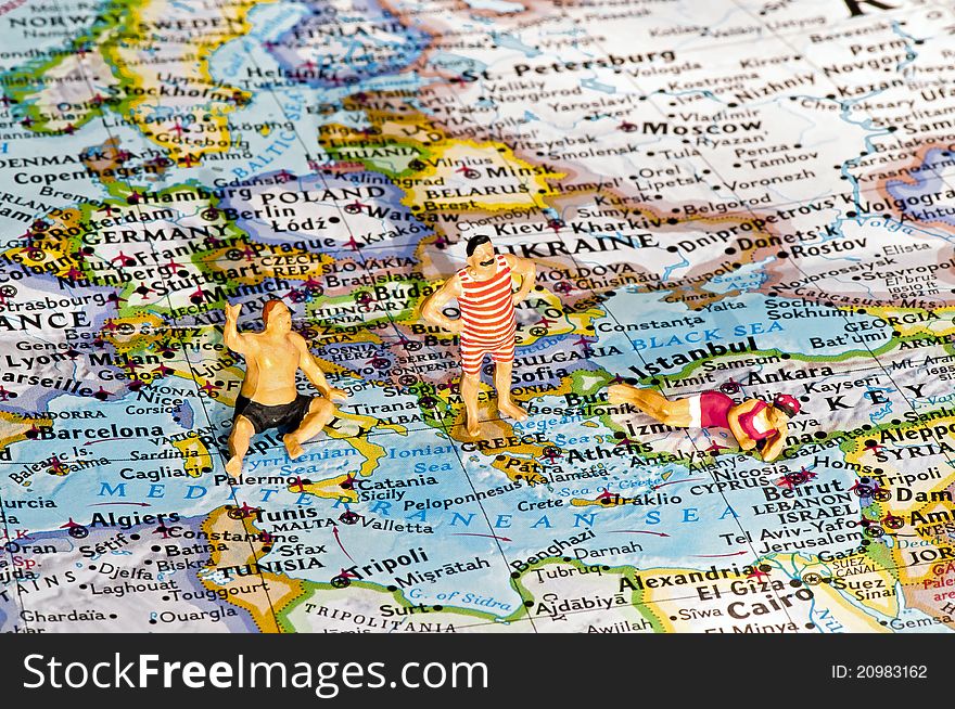 Beach tourists (figurines) on the map of Europe and Mediterranean Sea
