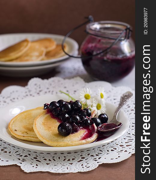 Pancakes with black currant jam topping on plate with fork. Selective focus