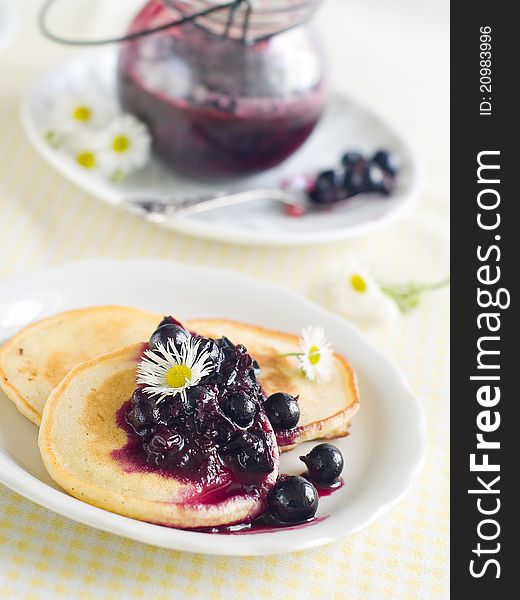 Pancakes with black currant jam topping on plate with fork. Selective focus