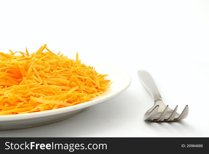 Grated carrot on a plate and fork. Grated carrot on a plate and fork