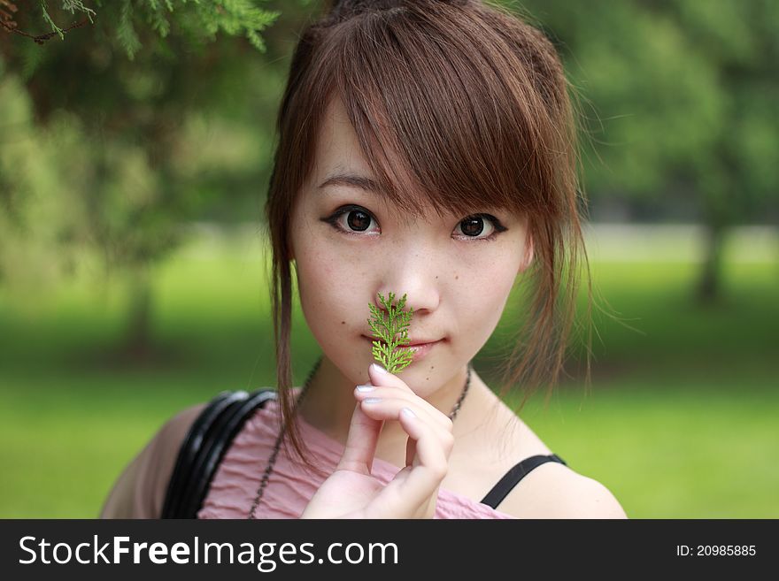 A lovely asian woman in a park’ grass plot.
