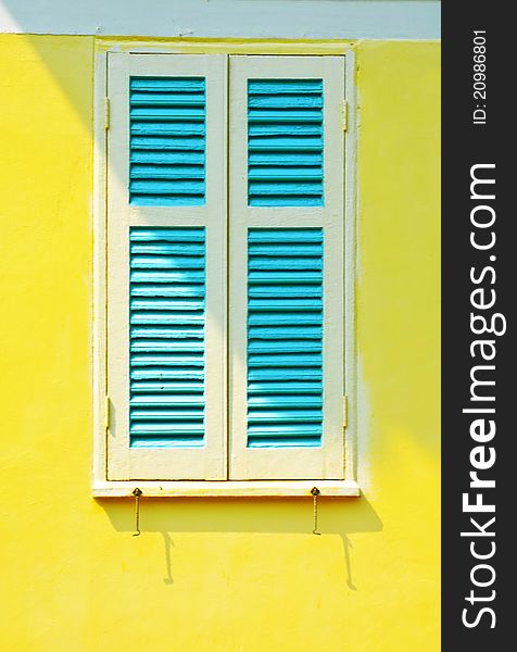 A window with bars on a yellow wall