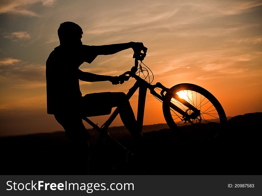 A cyclist riding in the last beams of a setting sun. A cyclist riding in the last beams of a setting sun