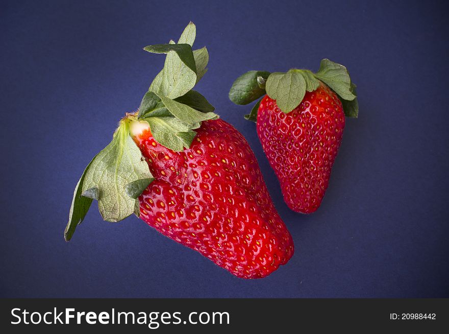 A pair of juicy strawberries on a blue background.