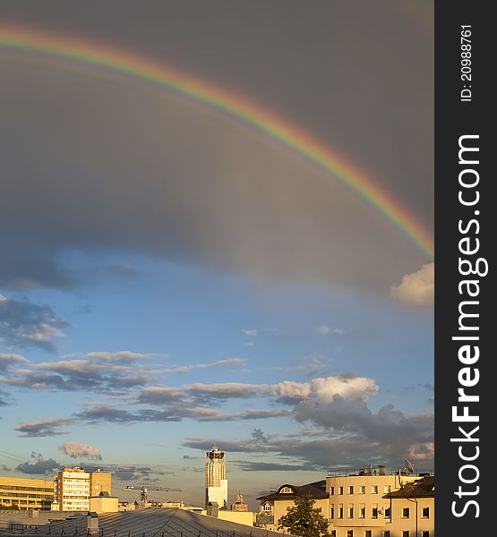 Rainbow on cloudy sky over city roofs
