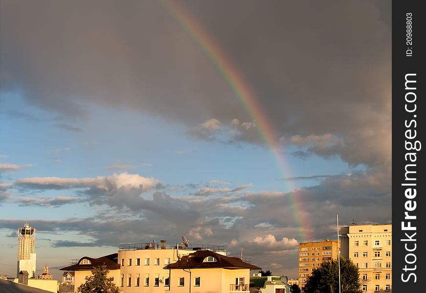 Rainbow on cloudy sky over city roofs