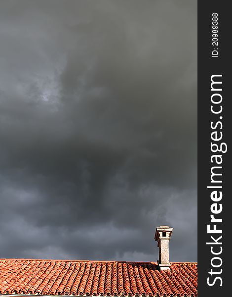 A chimney on a roof of a house with sky covered with clouds. A chimney on a roof of a house with sky covered with clouds