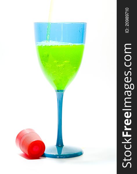 Yellow liquid being poured into a blue glass with red cap. Yellow liquid being poured into a blue glass with red cap.