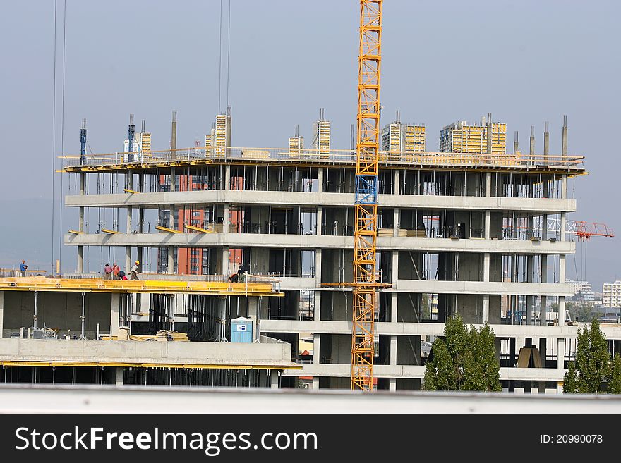 Building crane and building under construction against blue sky