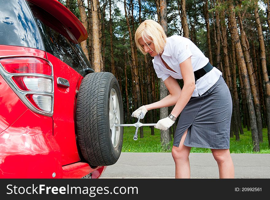 Blonde changing tire alone on a road. Blonde changing tire alone on a road