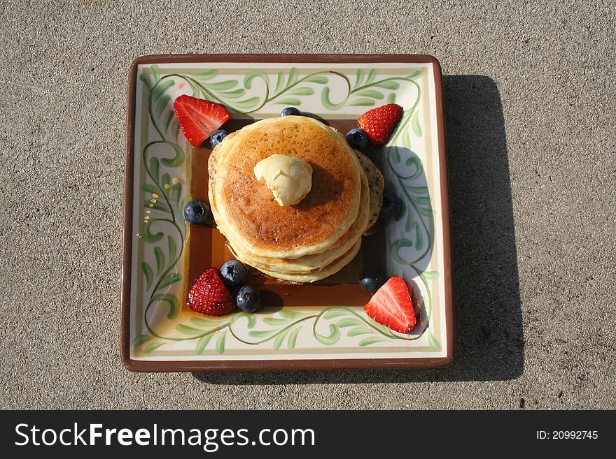 Pancakes on a plate with berries and syrup.