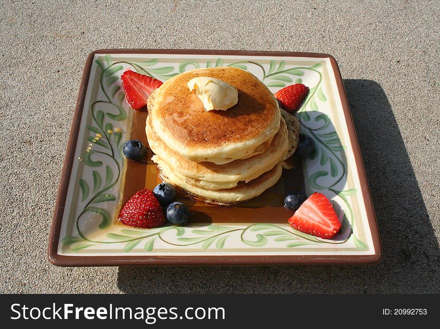 Pancakes on a plate with berries and syrup.