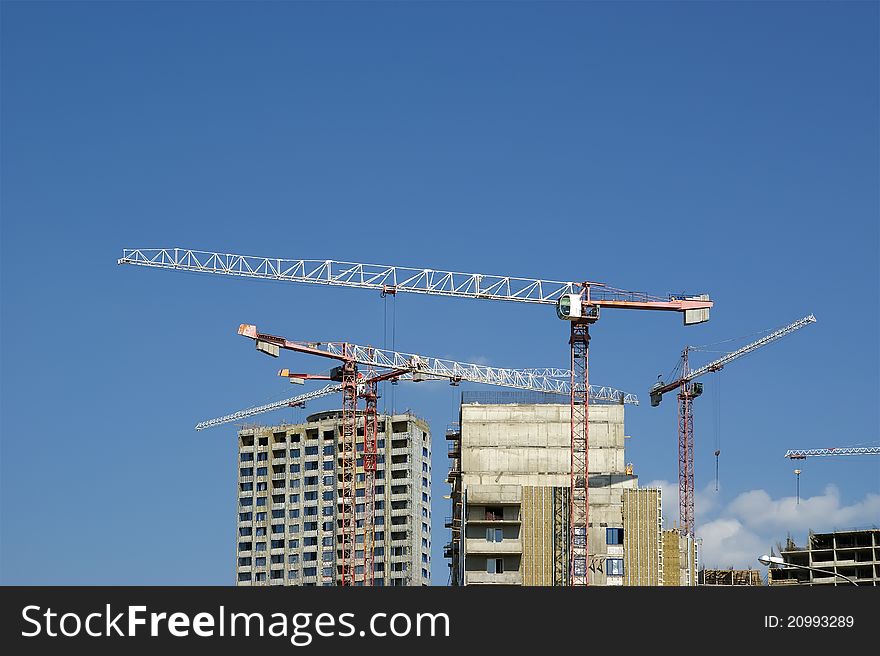 Building crane at the background of a multi-storey building under construction