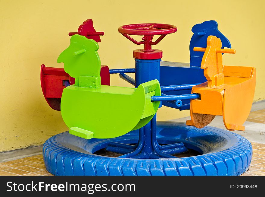 Colorful Children's roundabout with yellow wall. Colorful Children's roundabout with yellow wall