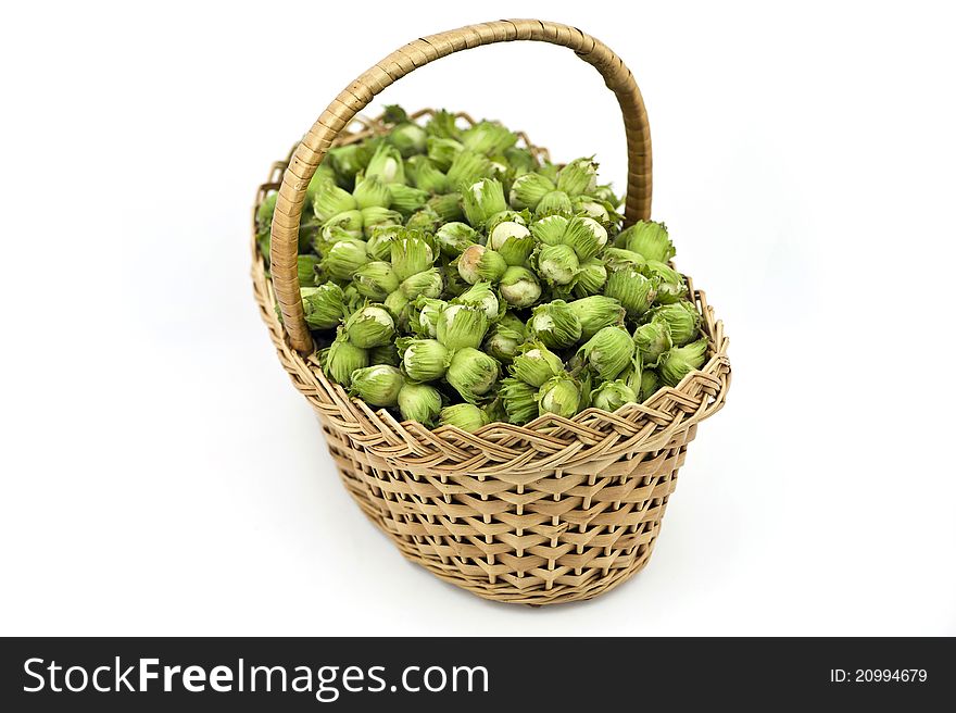 A wattled basket full of hazelnuts on the white background