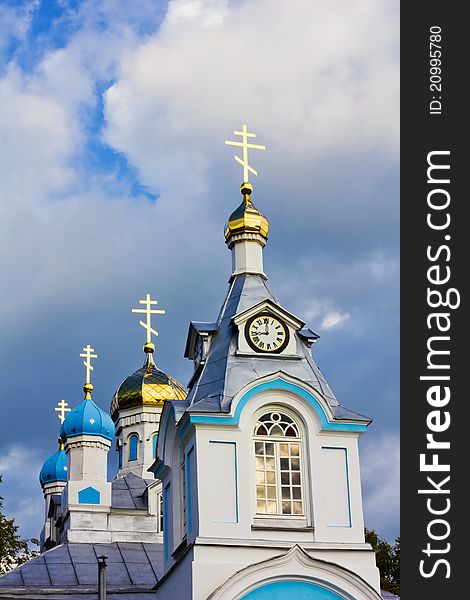 White orthodox church with gleaming crosses on a dark stormy sky