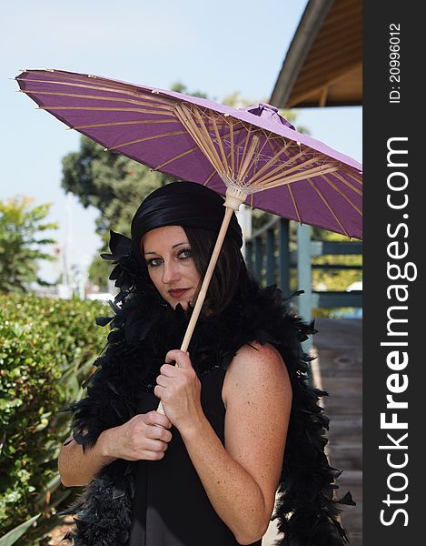 Beautiful Woman dressed in 1930/40's Vintage clothing, hat and boa holding a purple paper umbrella at an old train depot. Beautiful Woman dressed in 1930/40's Vintage clothing, hat and boa holding a purple paper umbrella at an old train depot.