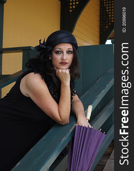 Close up of a Beautiful Woman dressed in 1930/40's Vintage clothing, hat and boa holding a purple paper umbrella at an old train depot. Close up of a Beautiful Woman dressed in 1930/40's Vintage clothing, hat and boa holding a purple paper umbrella at an old train depot.