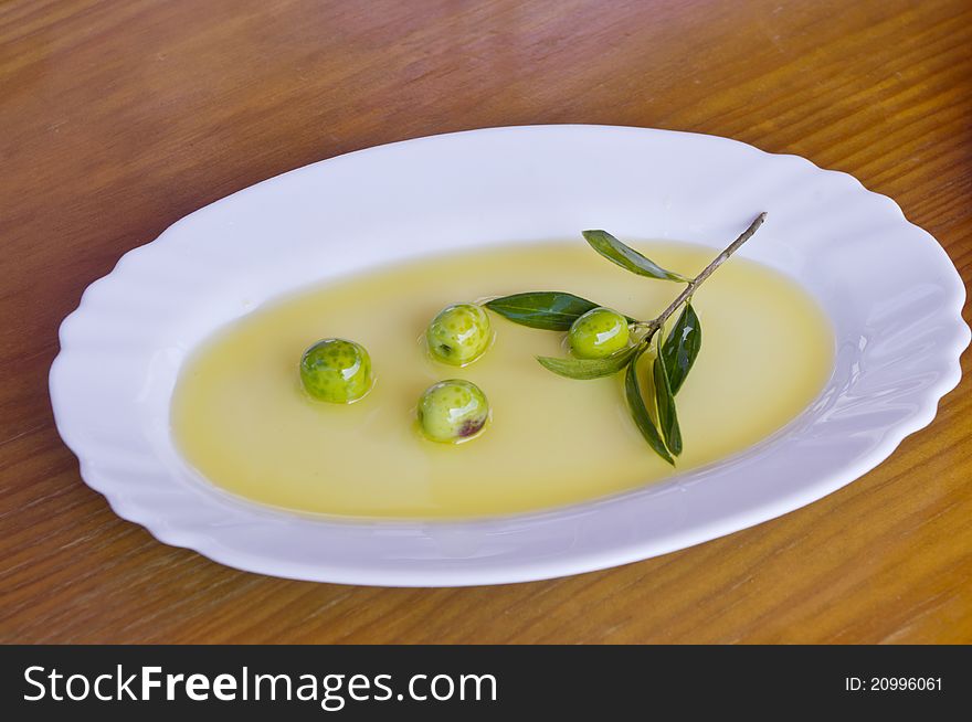 Olive branch with olive oil on a wooden background. Olive branch with olive oil on a wooden background