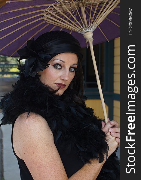 Close up of a Beautiful Woman dressed in 1930/40's Vintage clothing, hat and boa holding a purple paper umbrella at an old train depot. Close up of a Beautiful Woman dressed in 1930/40's Vintage clothing, hat and boa holding a purple paper umbrella at an old train depot.