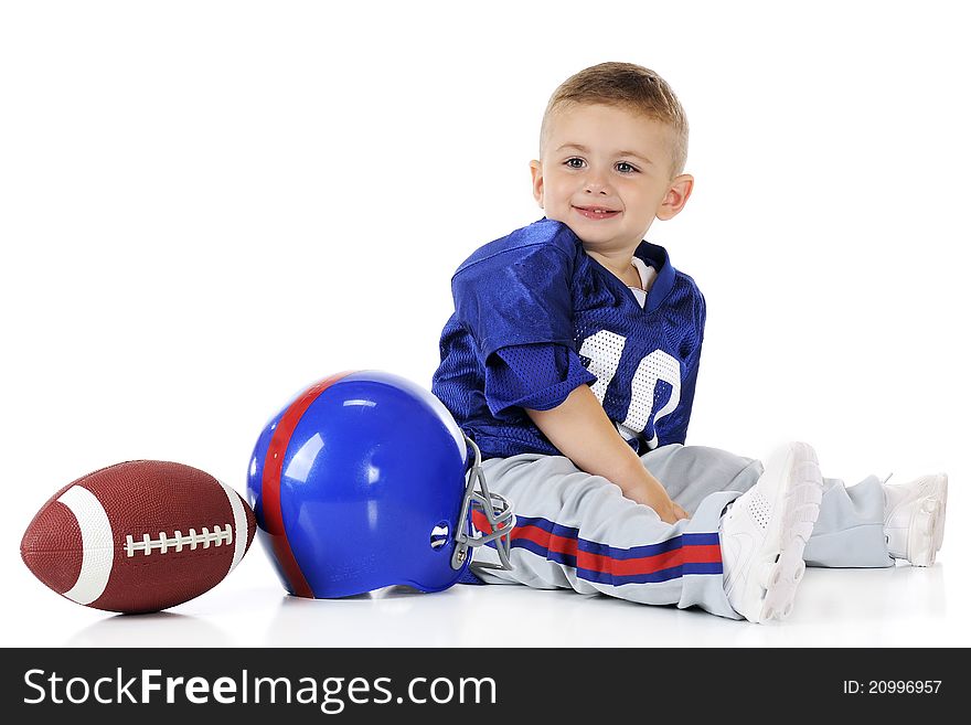 An adorable toddler in his football uniform by his helmet and football. Isolated on white. An adorable toddler in his football uniform by his helmet and football. Isolated on white.