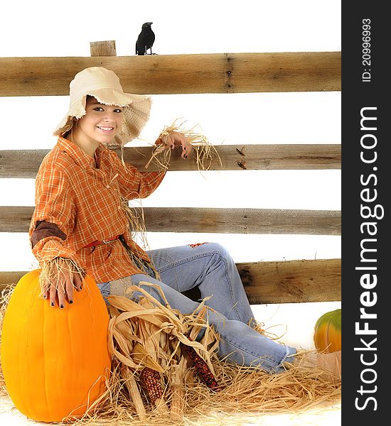 A living teen scarecrow flopped on a pile of hay by a rustic rail fence. Pumpkins and an old crow are nearby. A living teen scarecrow flopped on a pile of hay by a rustic rail fence. Pumpkins and an old crow are nearby.