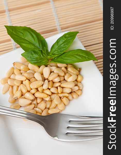 Healthy pine seeds on white plate with fork. Commonly used in pasta sauces. Healthy pine seeds on white plate with fork. Commonly used in pasta sauces.