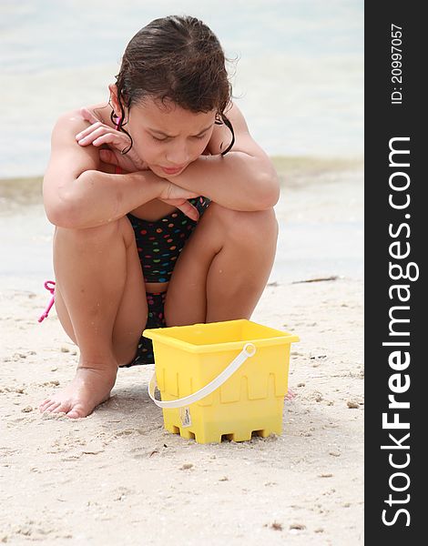 Girl who has caught a hermit crab at the beach in her sand bucket. Girl who has caught a hermit crab at the beach in her sand bucket