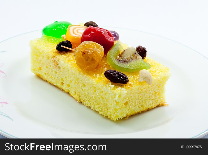 A piece of cake garnished with various kinds of fruits