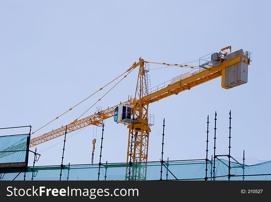 Construction crane on building site with scafolding in foreground