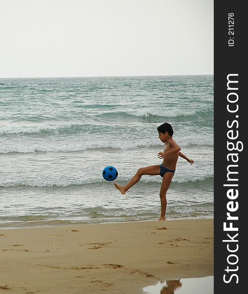 Young boy playing soccer on beach. Young boy playing soccer on beach