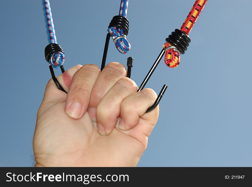 Hand pulling on 3 bungee cords tight. Hand pulling on 3 bungee cords tight