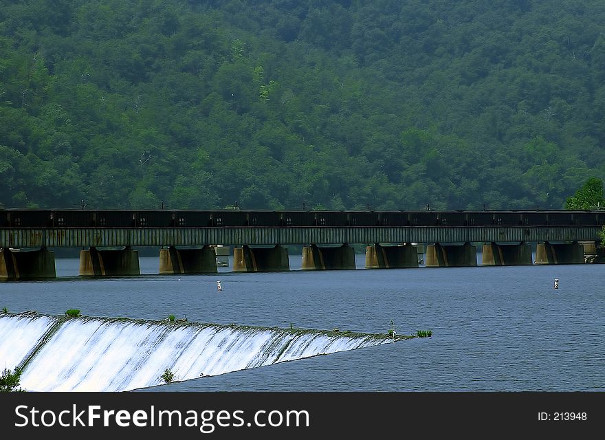 Man made water fall for a hydro-electric plant.. train on bridge in the background. Man made water fall for a hydro-electric plant.. train on bridge in the background.