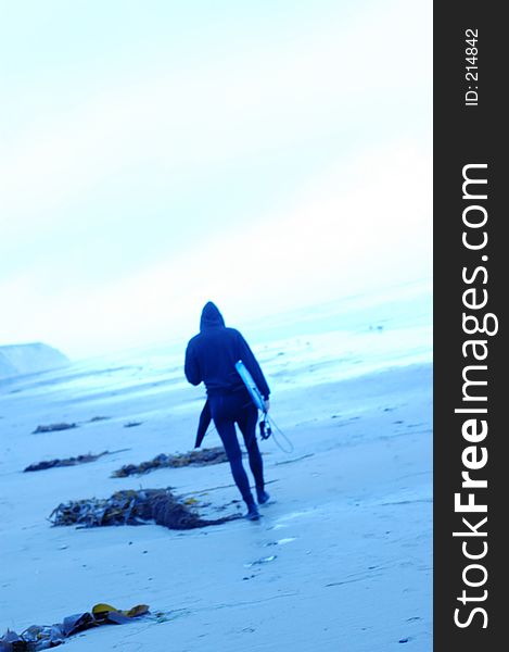 Soft focus blue toned images of surfers. Single surfer walking. Soft focus blue toned images of surfers. Single surfer walking.