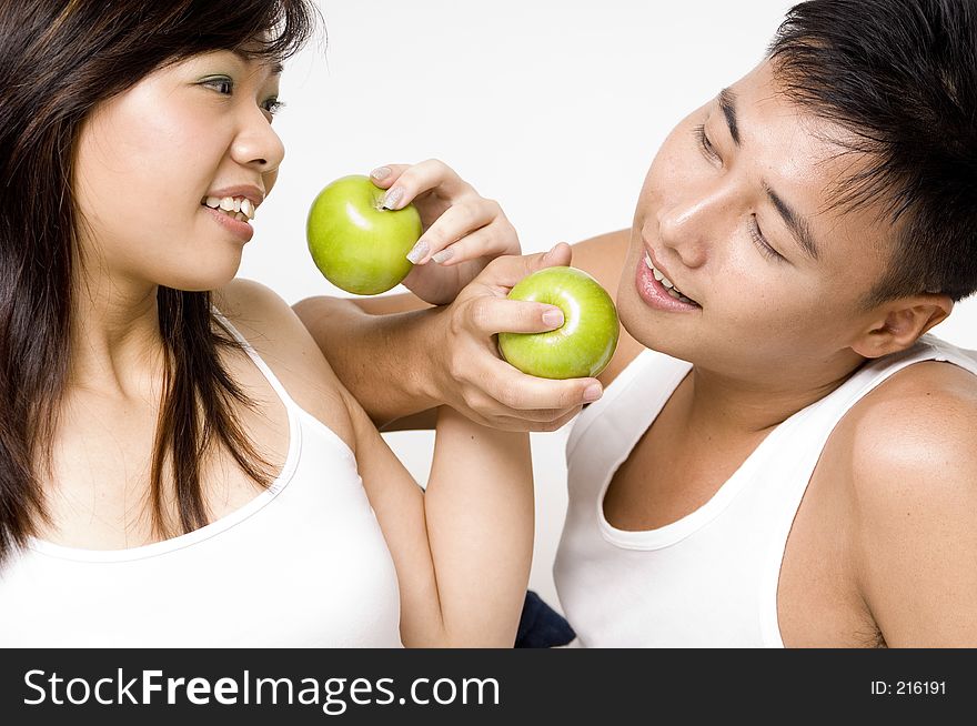 A healthy-looking chinese young couple share some apples with love. A healthy-looking chinese young couple share some apples with love