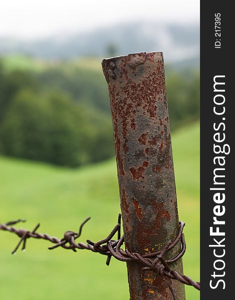 Rusty metal post with barb wire