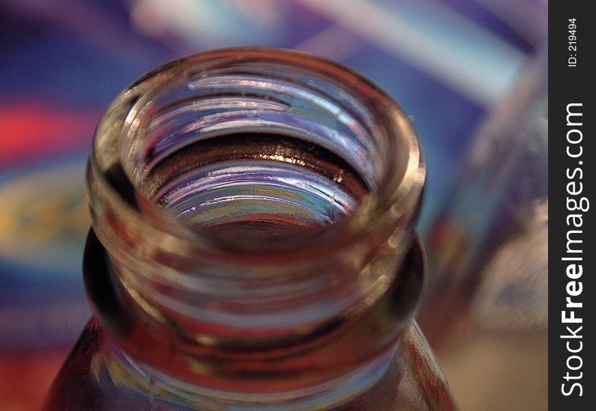 Colorful light plays on open bottle in an extreme close-up with very shallow depth of field focusing just inside the mouth of the bottle. Colorful light plays on open bottle in an extreme close-up with very shallow depth of field focusing just inside the mouth of the bottle.