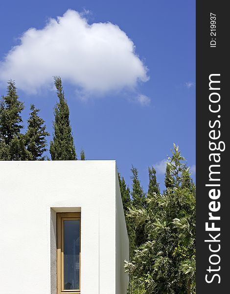 New, white building with slim window, fir trees and blue sky with one cloud. New, white building with slim window, fir trees and blue sky with one cloud